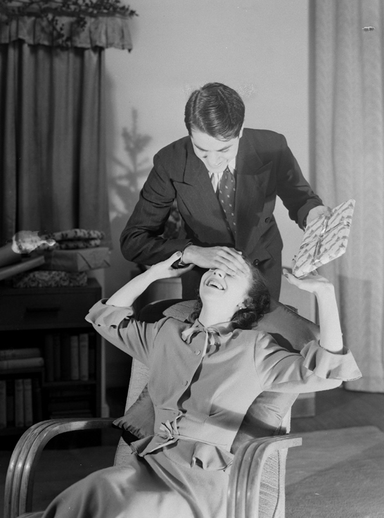 Man surprising a woman with a Christmas present, c.1950, Photographic Advertising Limited © National Media Museum, Bradford / SSPL. Creative Commons BY-NC-SA