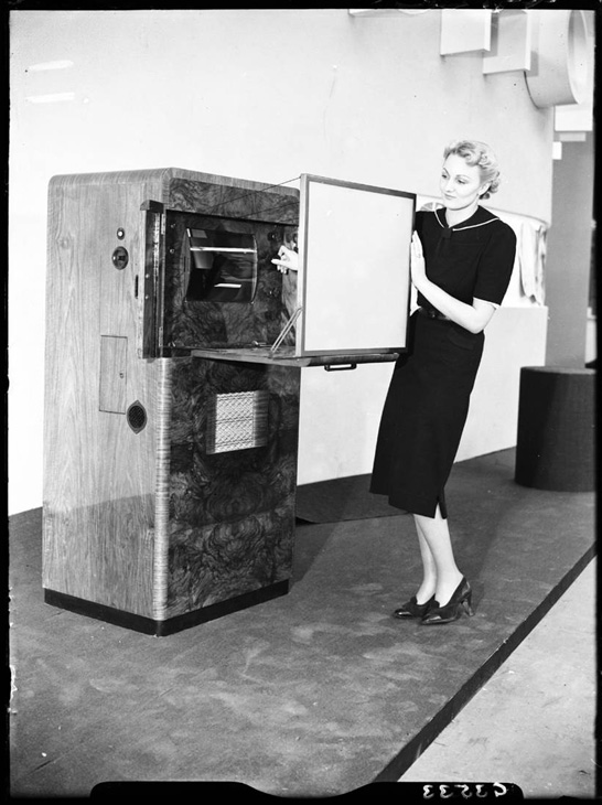 A model demonstrates the Ekco-Scophony ES104 television receiver on Scophony's stand at Radiolympia, 23 August 1938, Edward George Malindine © Daily Herald / National Media Museum, Bradford / SSPL