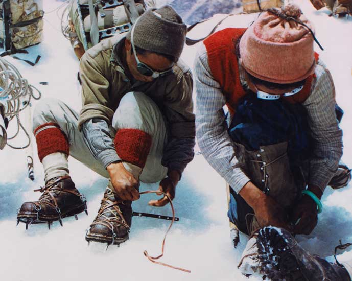 Two of the 34 Sherpas on the expedition attaching crampons to their boots.