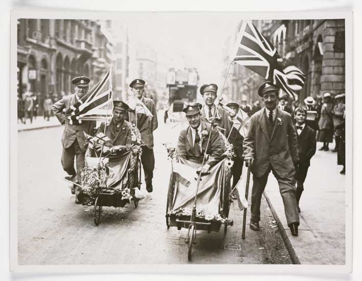 Peace scenes in London, with wounded soldiers in wheelchairs waving with flags