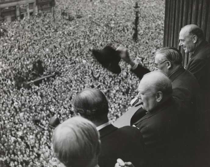 Churchill waving to the crowd on VE Day from a balcony along Whitehall
