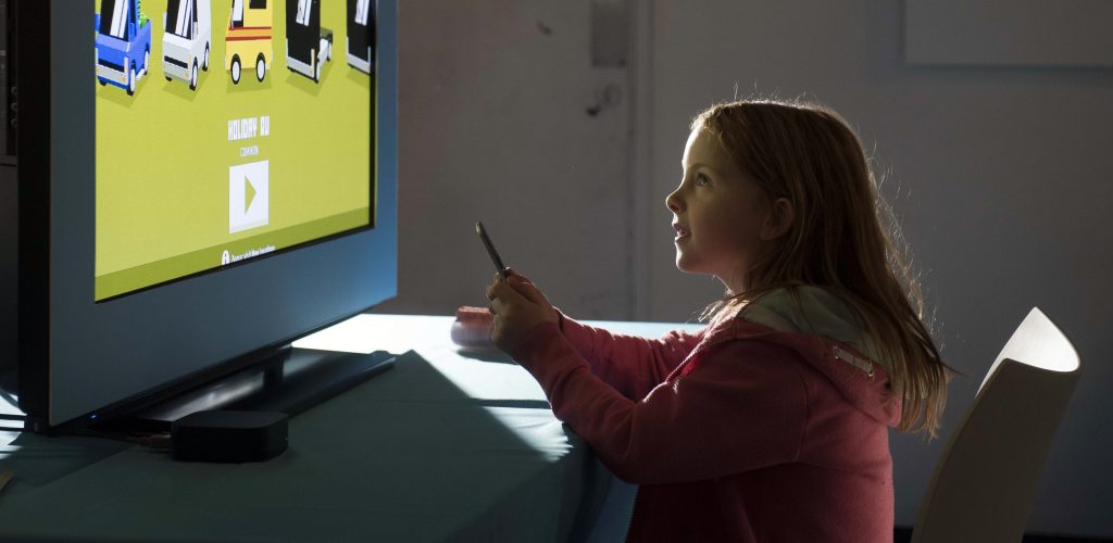 Image shows a young girl playing a computer game