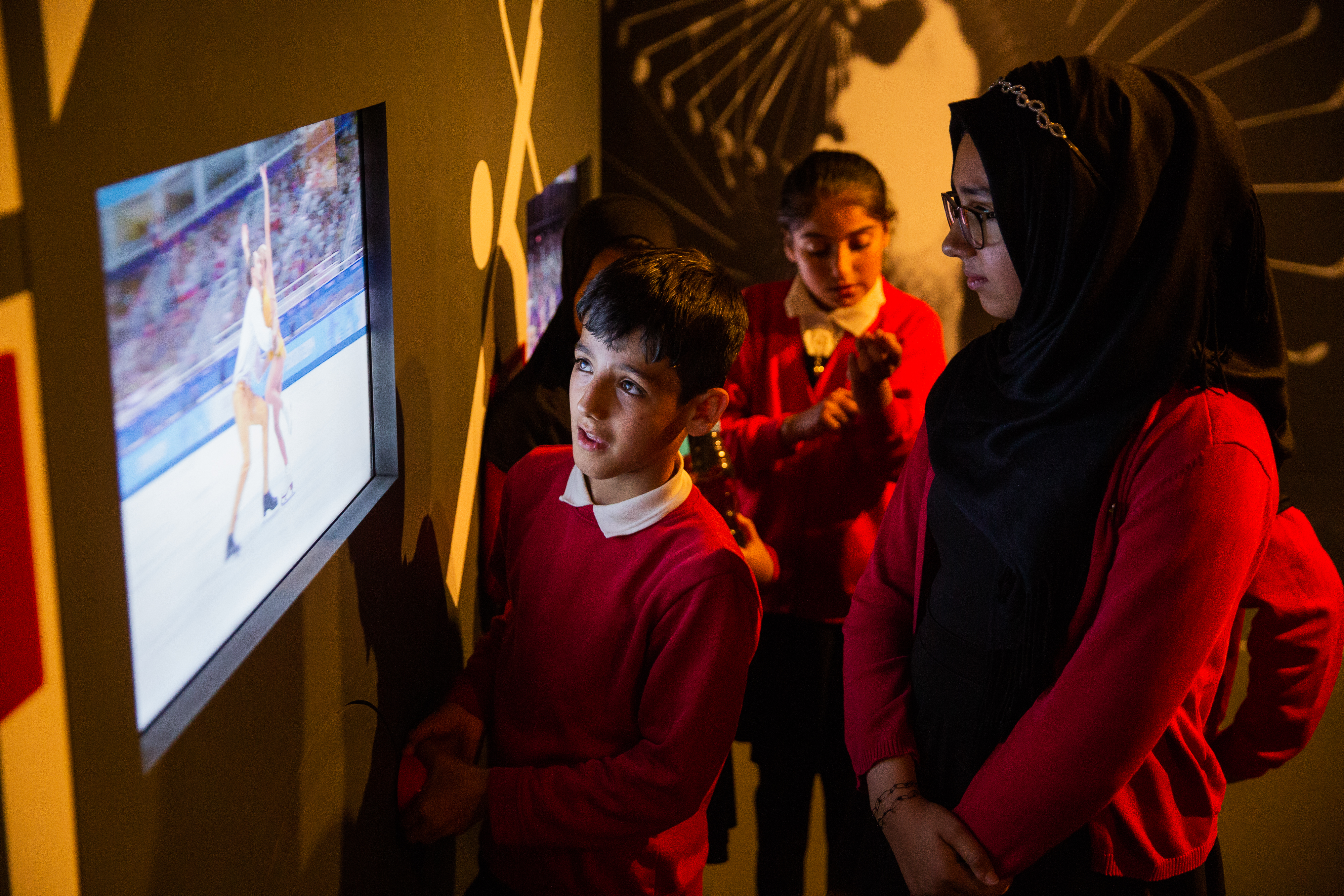 Students watch an interactive display at the Action Replay exhibition