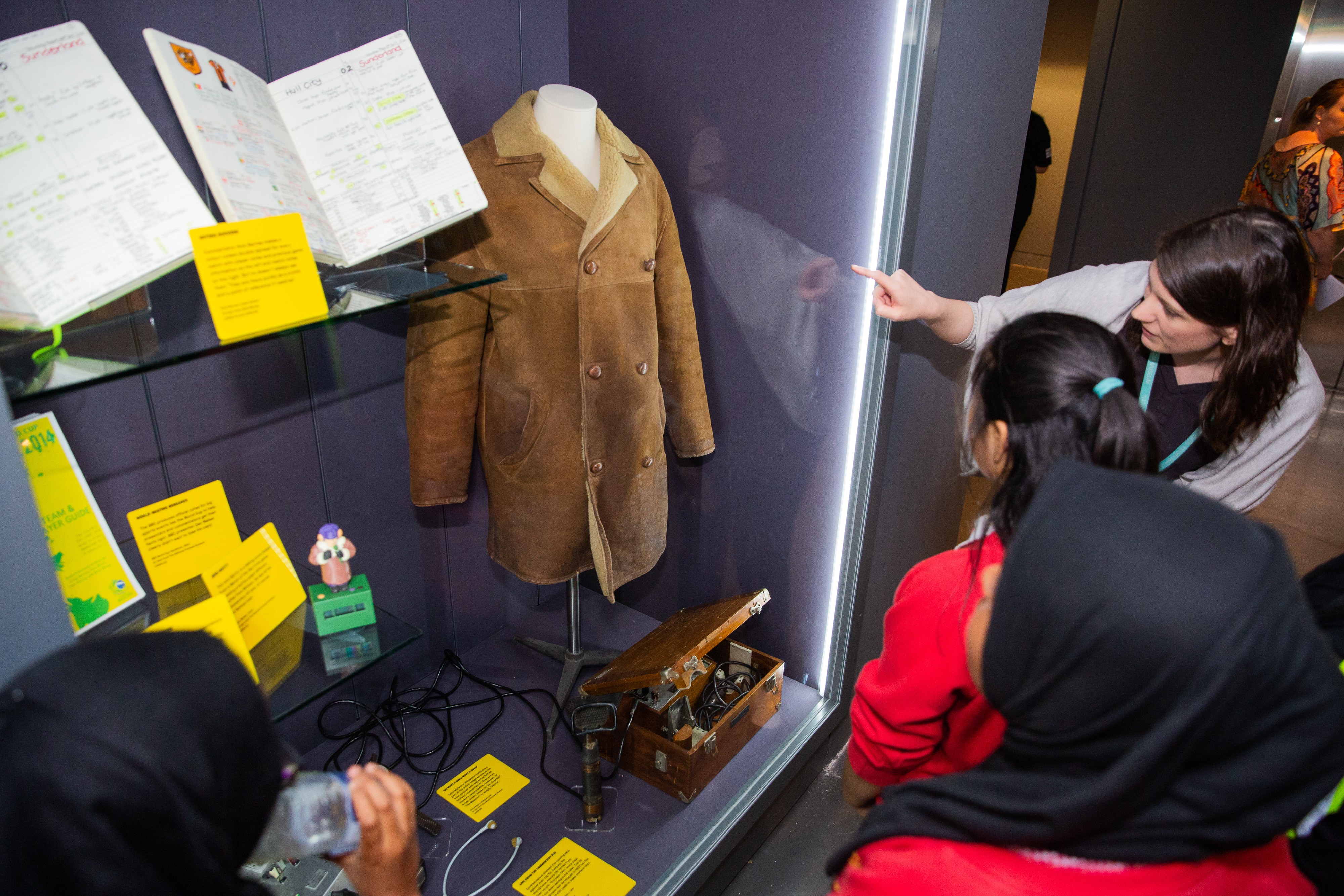 Students look at objects displayed at the Action Replay exhibition