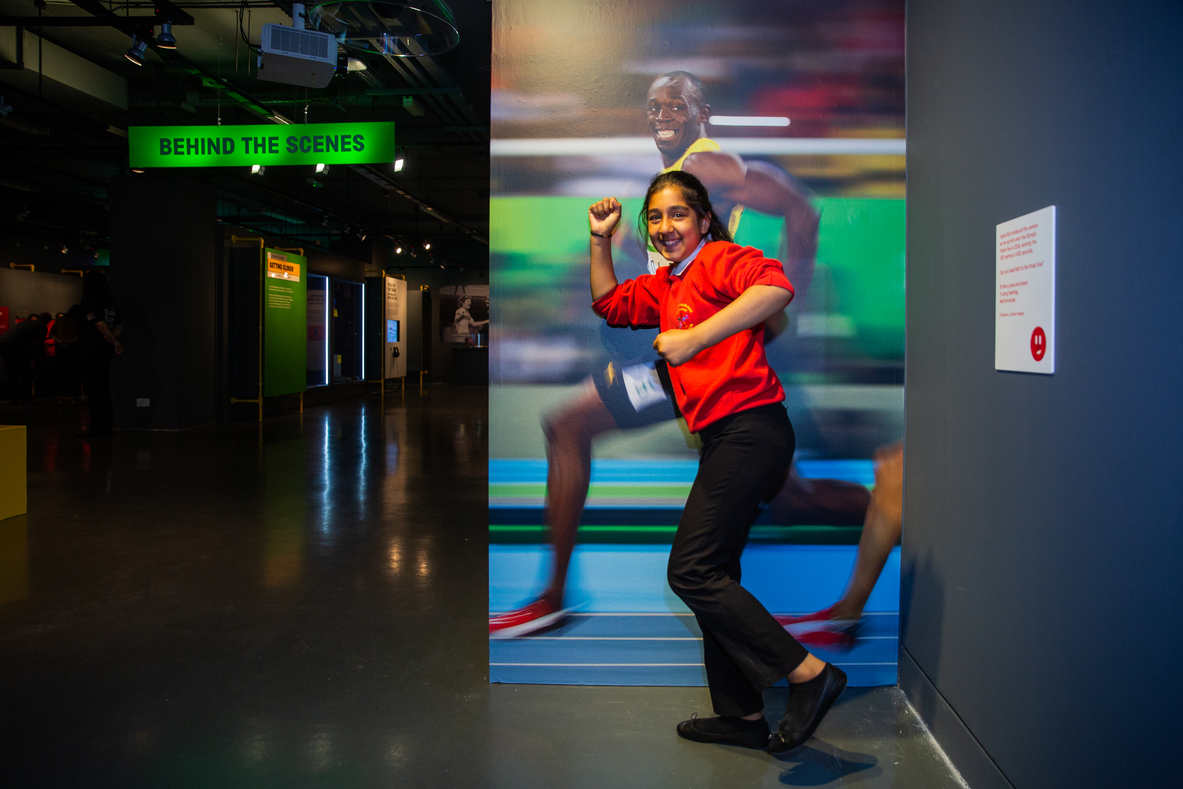 A student poses in front of a life-size image of sprinter Usain Bolt at the Action Replay exhibition
