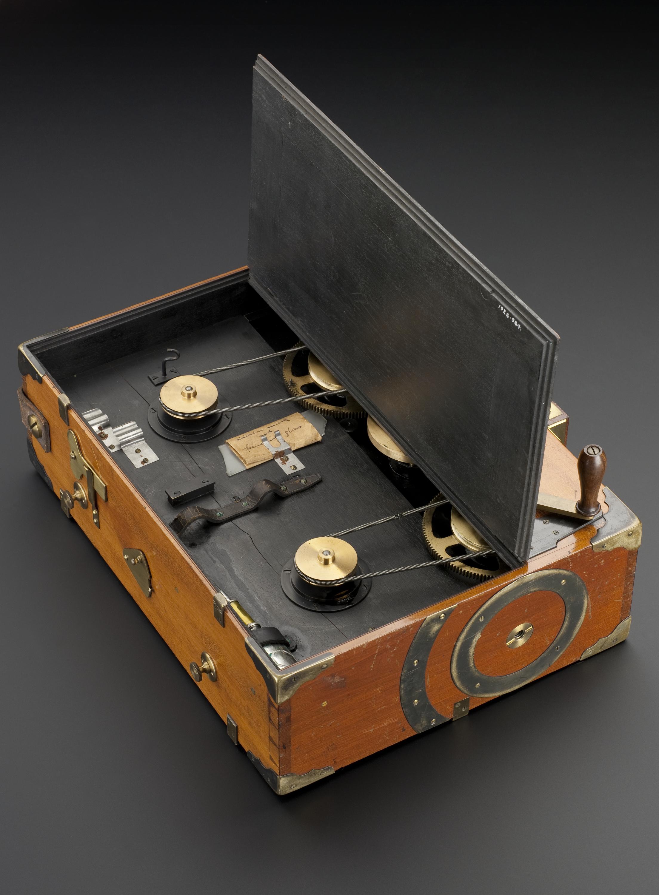Prestwich cinematographic camera, used by Mr H.G. Ponting in Scott's Antarctic Expedition, 1910. Front 3/4 view of whole object (open) against dark grey graduated background.