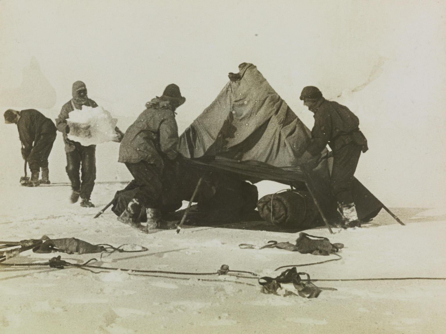 A photograph of Captain Robert Falcon Scott and his companions pitching a tent using ice to ballast down the tent sides