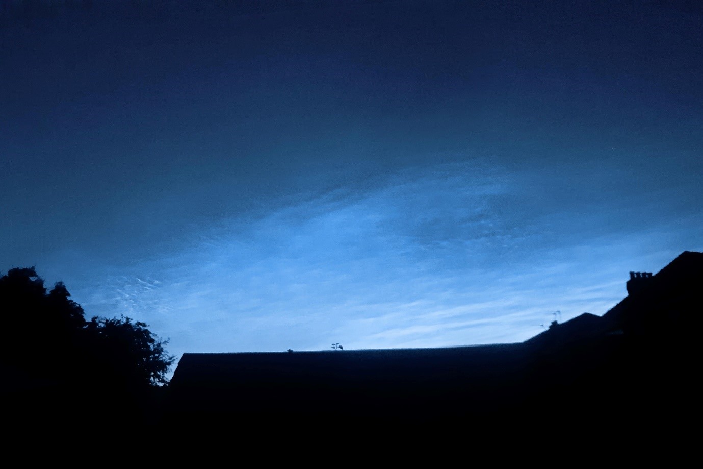 Noctilucent clouds visible in a dark blue night sky