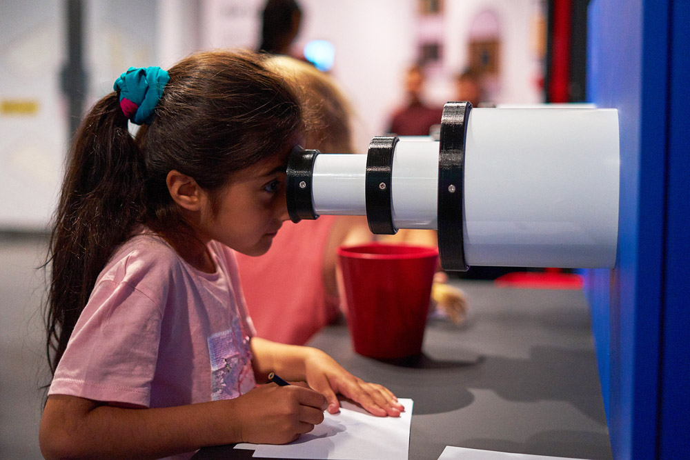 A girl looking through a telescope