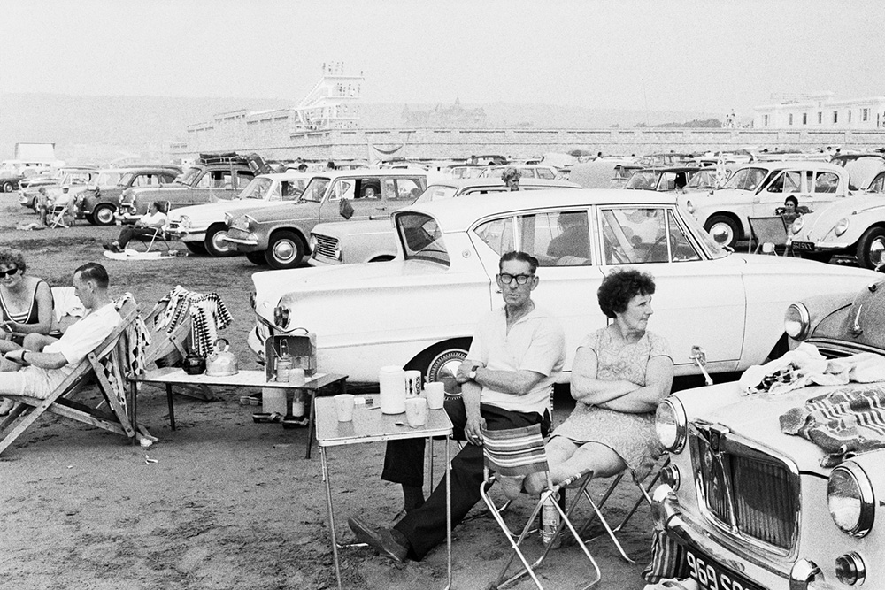Couple sat at a portable table with cars in background
