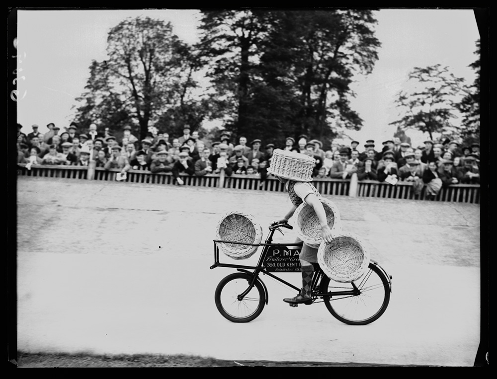 Sports day competitor cycling with a basket on their head