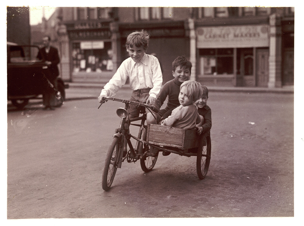 Four children riding a bicycle and sidecar