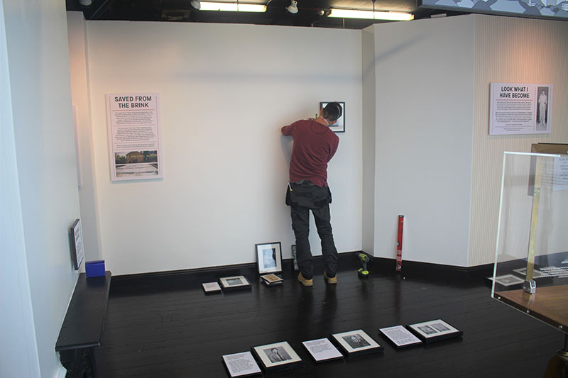 Art technician placing photographs on wall