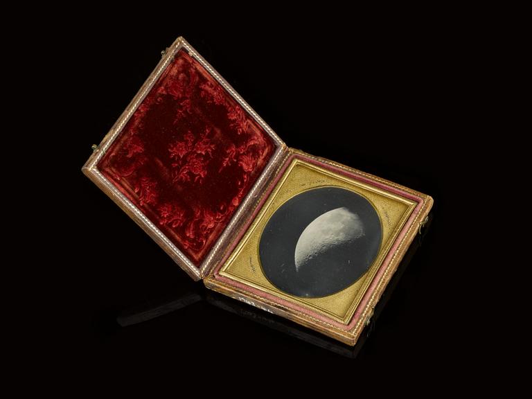 A daguerreotype of the moon in a gold and red case