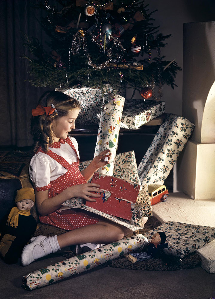 Girl with presents underneath Christmas tree