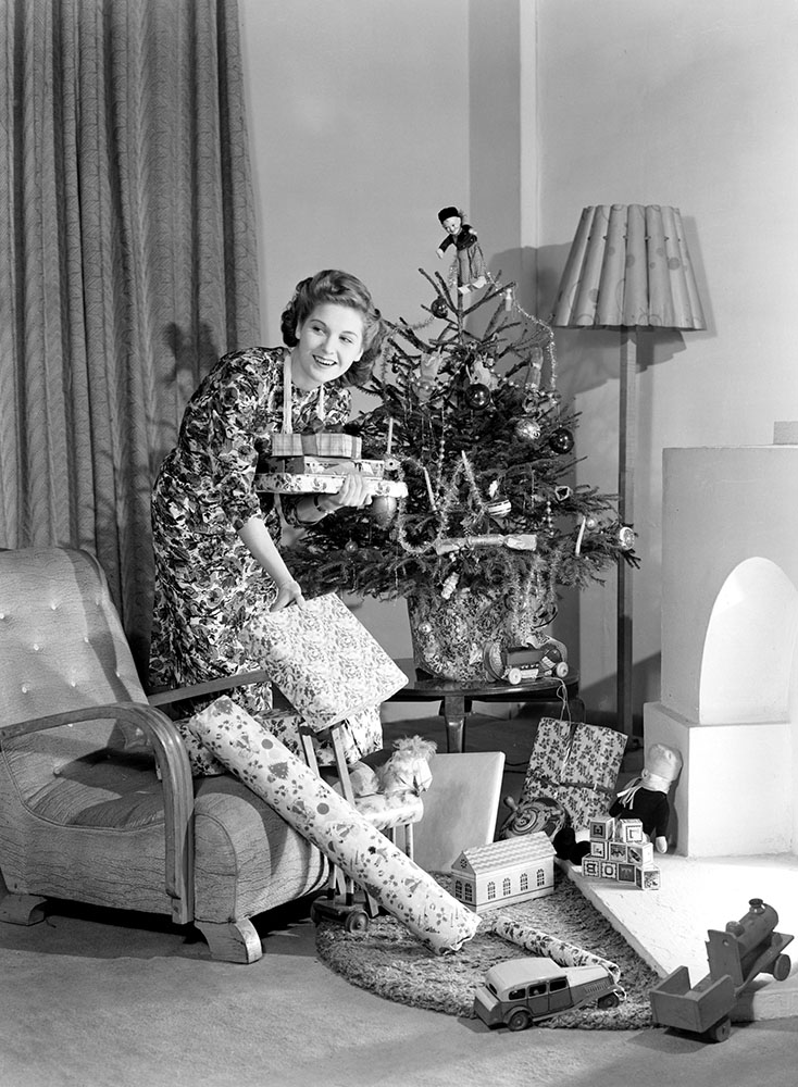 Woman putting Christmas presents under a tree