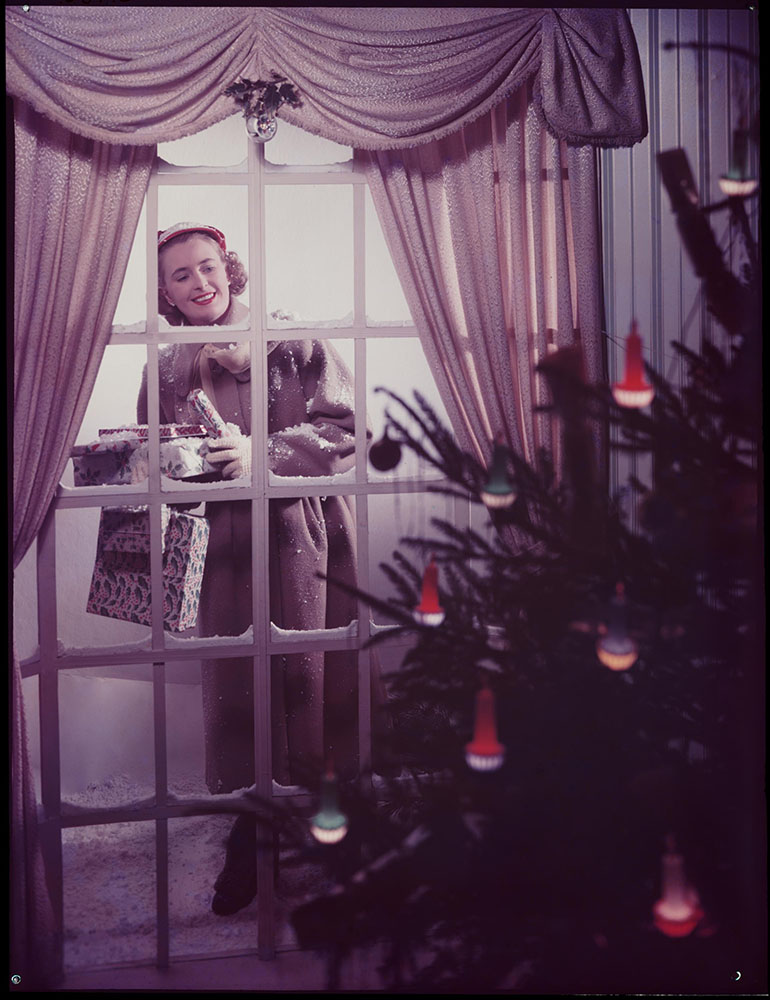 Woman looking through a window at a Christmas tree