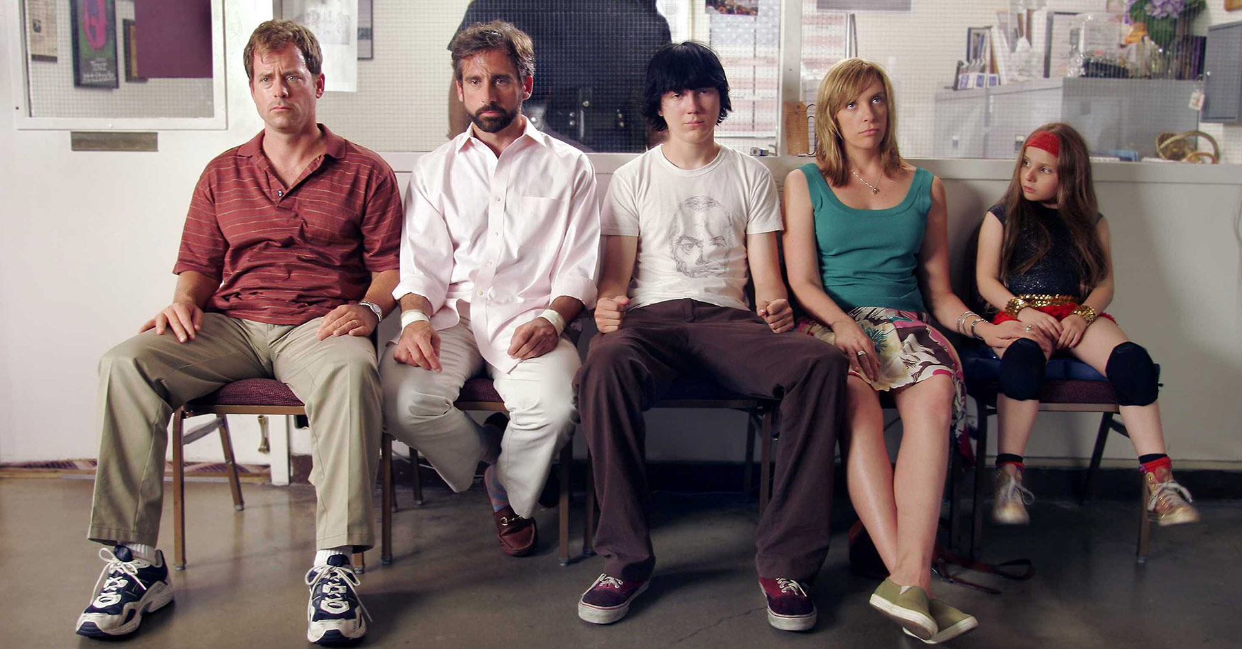 A family of five people sit next to each other in a waiting area