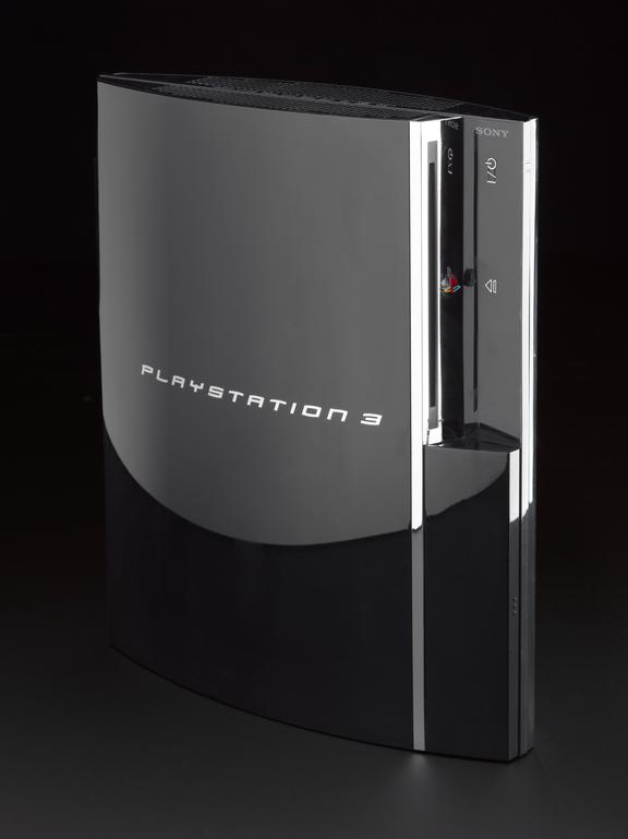 A shiny black games console with silver details against a black background
