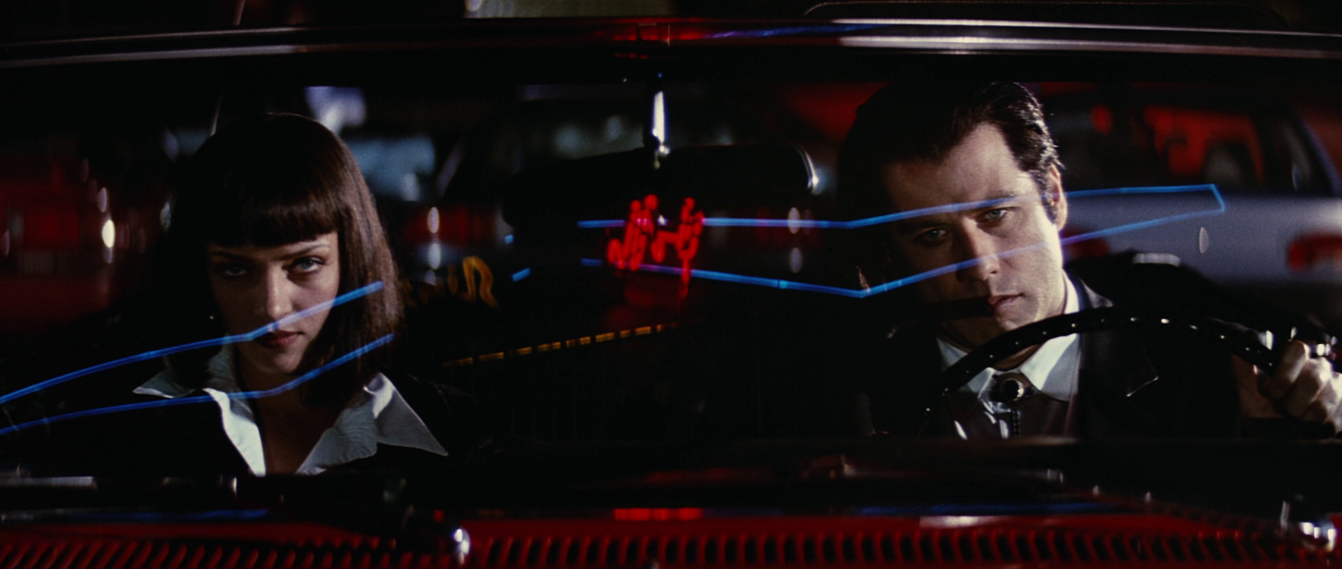John Travolta drives a convertible sports car with Uma Thurman in the passenger seat in Pulp Fiction