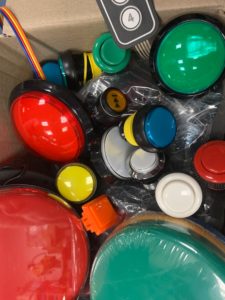 a cardboard box full of lots of colourful round push buttons in different sizes