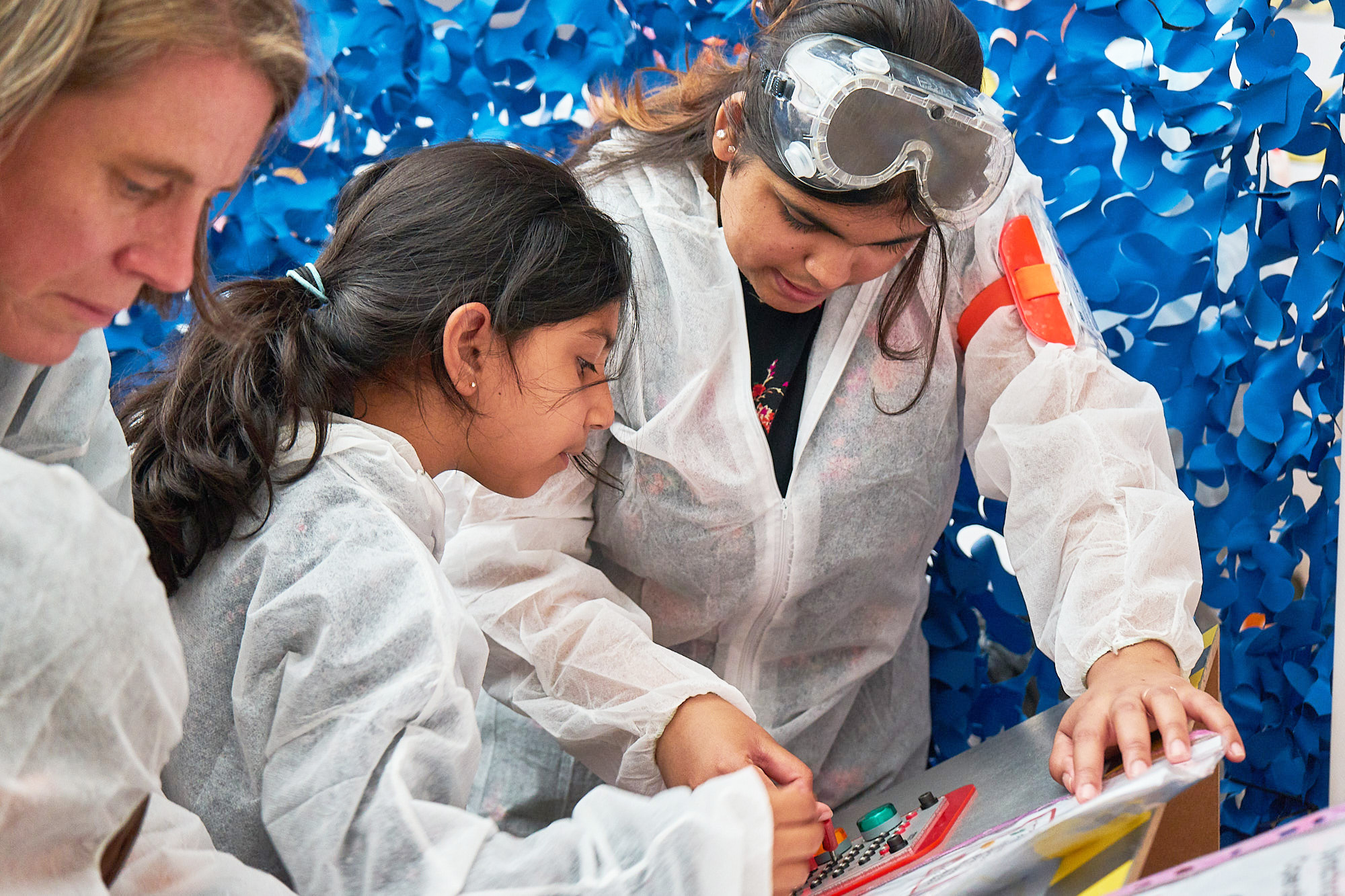 Children wearing white boiler suits participate in a science activity