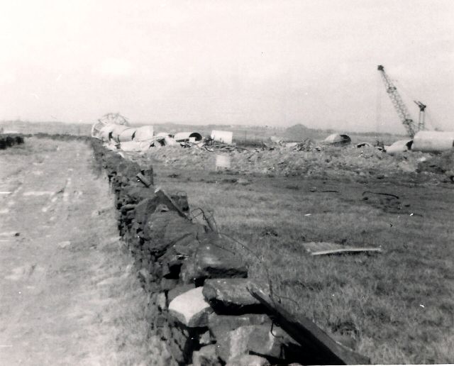 Black and white photograph of building debris strewn across a field
