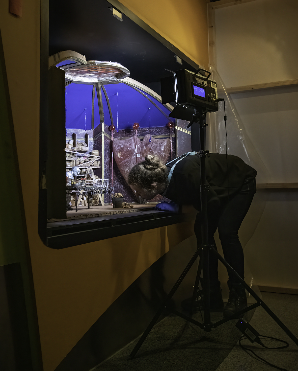 A collections team member leans over to look closely at an animation set, lit by a task lamp