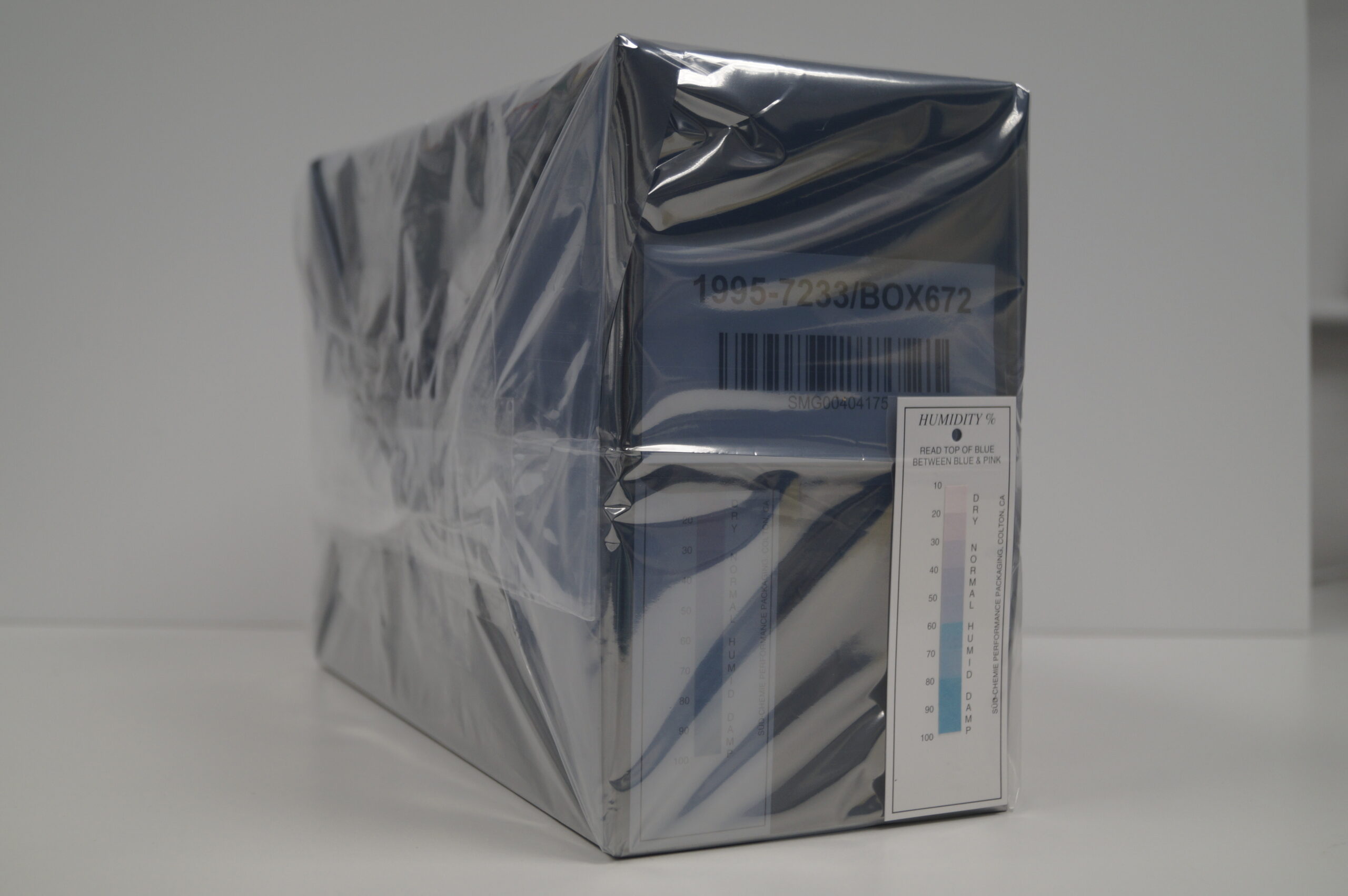 A black box wrapped in clear plastic with a white card showing a colour humidity scale