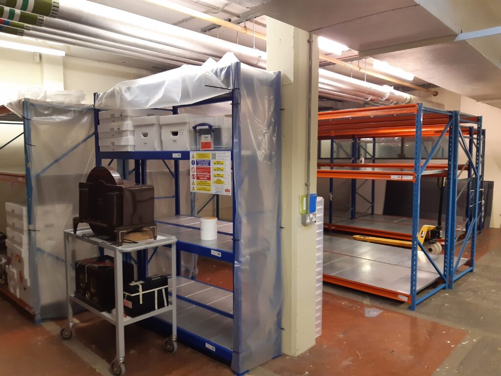 A basement storeroom with metal shelving and strip lighting