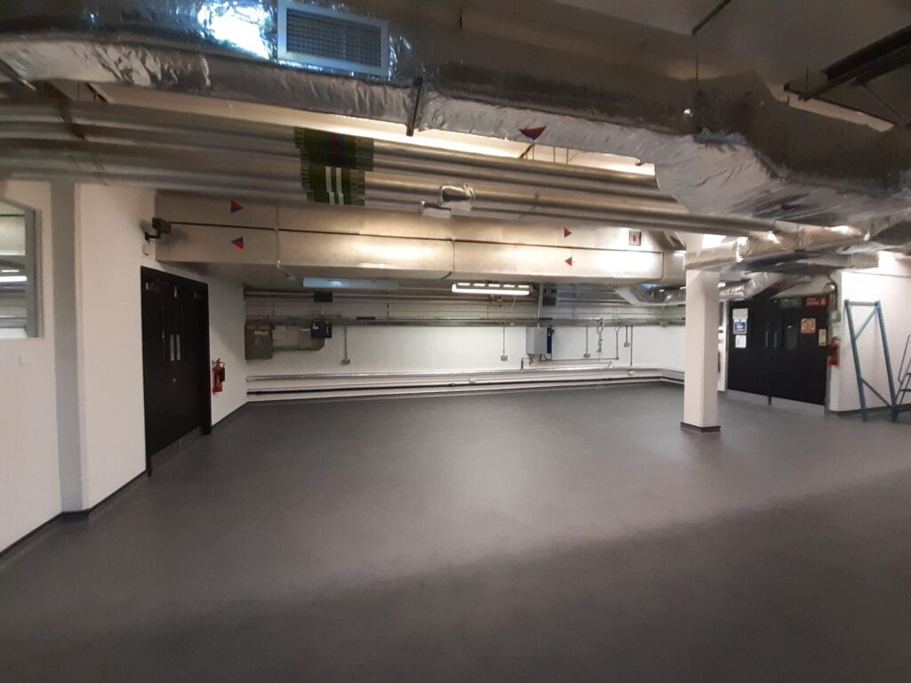 An empty basement storeroom with new grey flooring
