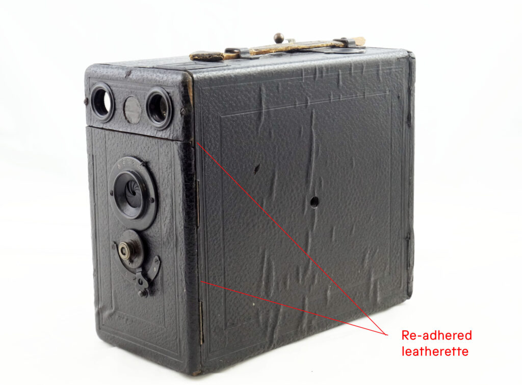 A box camera with red annotation showing where the covering material has been reattached