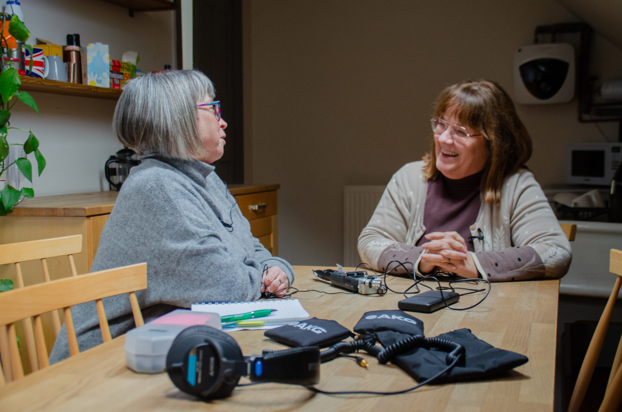 Two older women sat at a table, with sound recording equipment