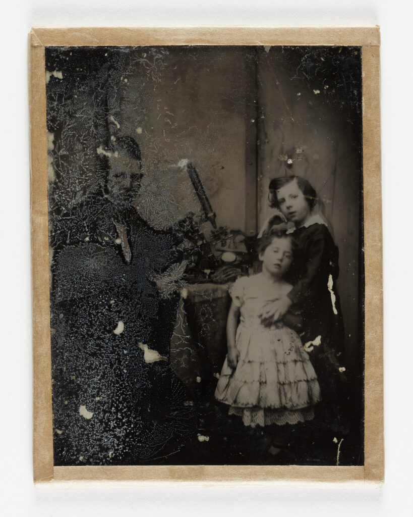 Old, damaged photo of a man and two children.