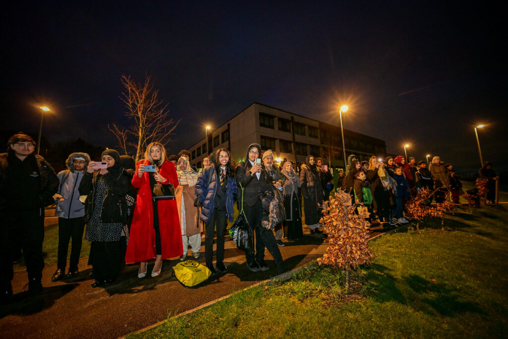 A group of school students outside their school at night