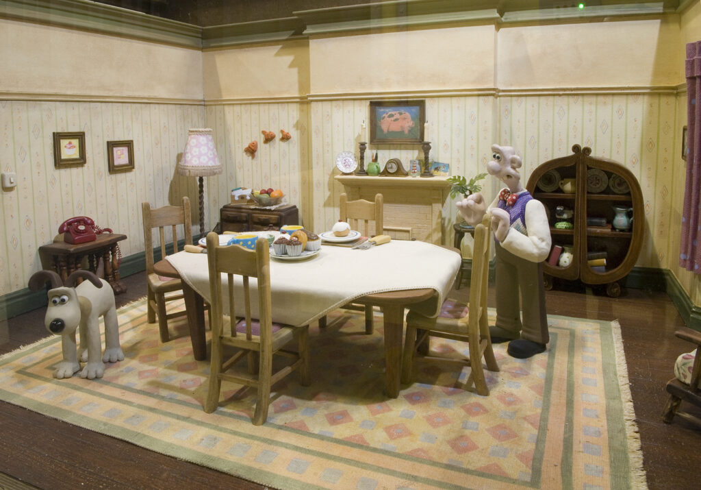 Wallace's living room, with dining table, fireplace and Gromit standing on the rug