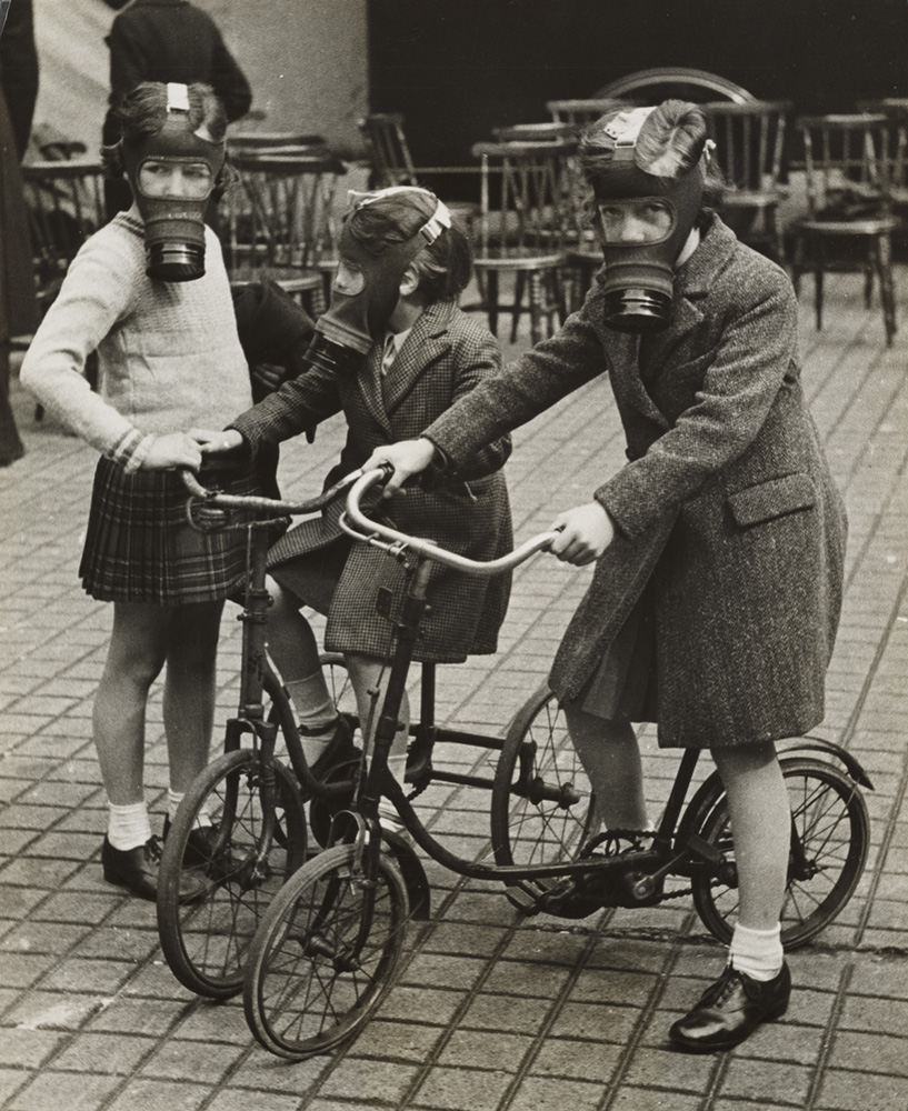 Children cycling, wearing their gas masks