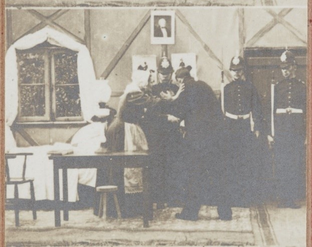 Frame from a film showing a man, woman and three police officers