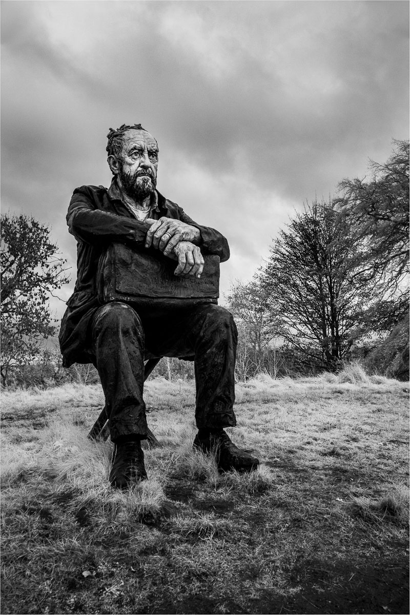 Large sculpture of a male figure sitting down
