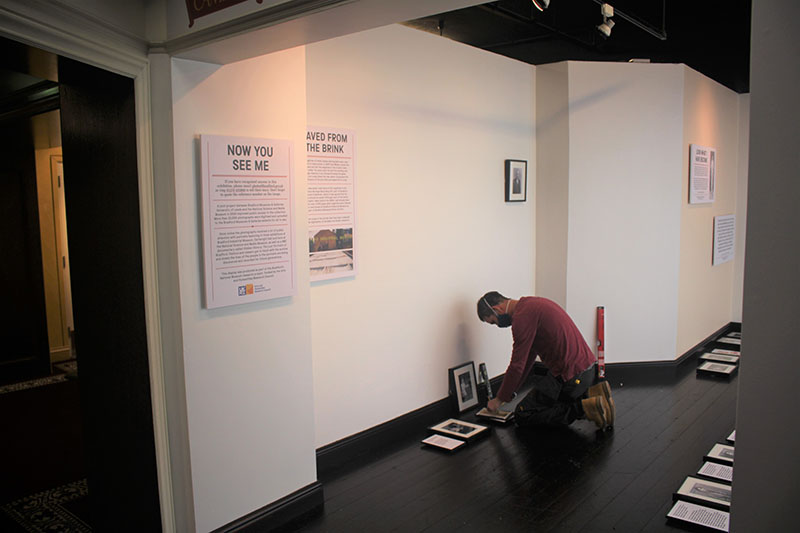 Art technician placing photographs on wall