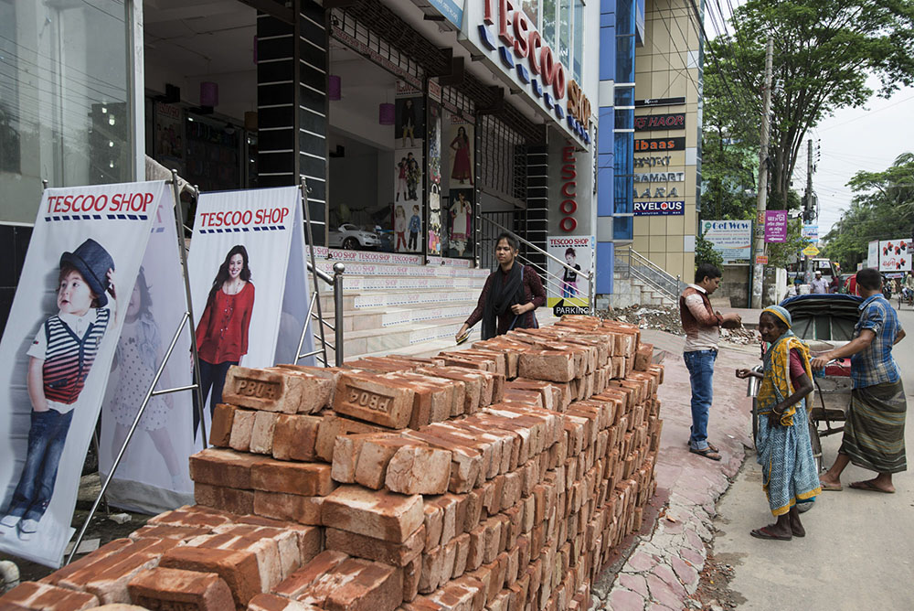 A passenger pays for his rickshaw ride outside the Tescoo Shop in Sylhet City
