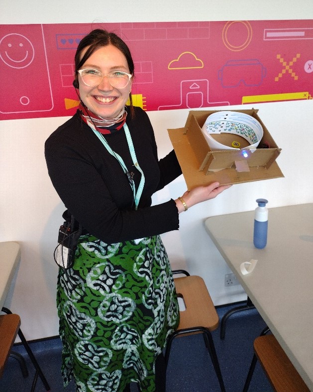 Smiling person holds up a cardboard model