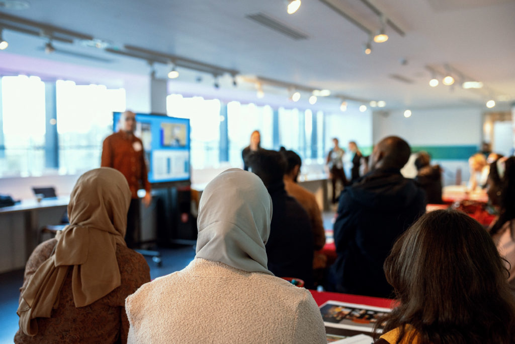 A seated group of people listen to a presentation