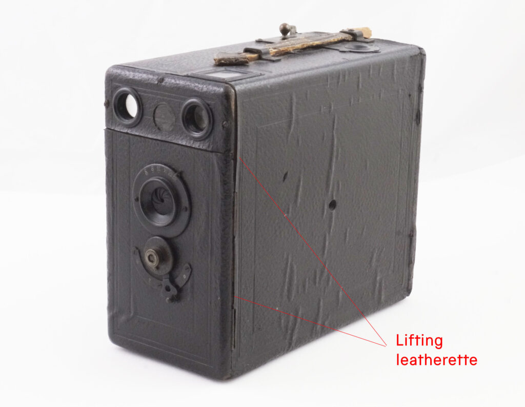 A box camera with red annotation showing where the covering material is peeling away