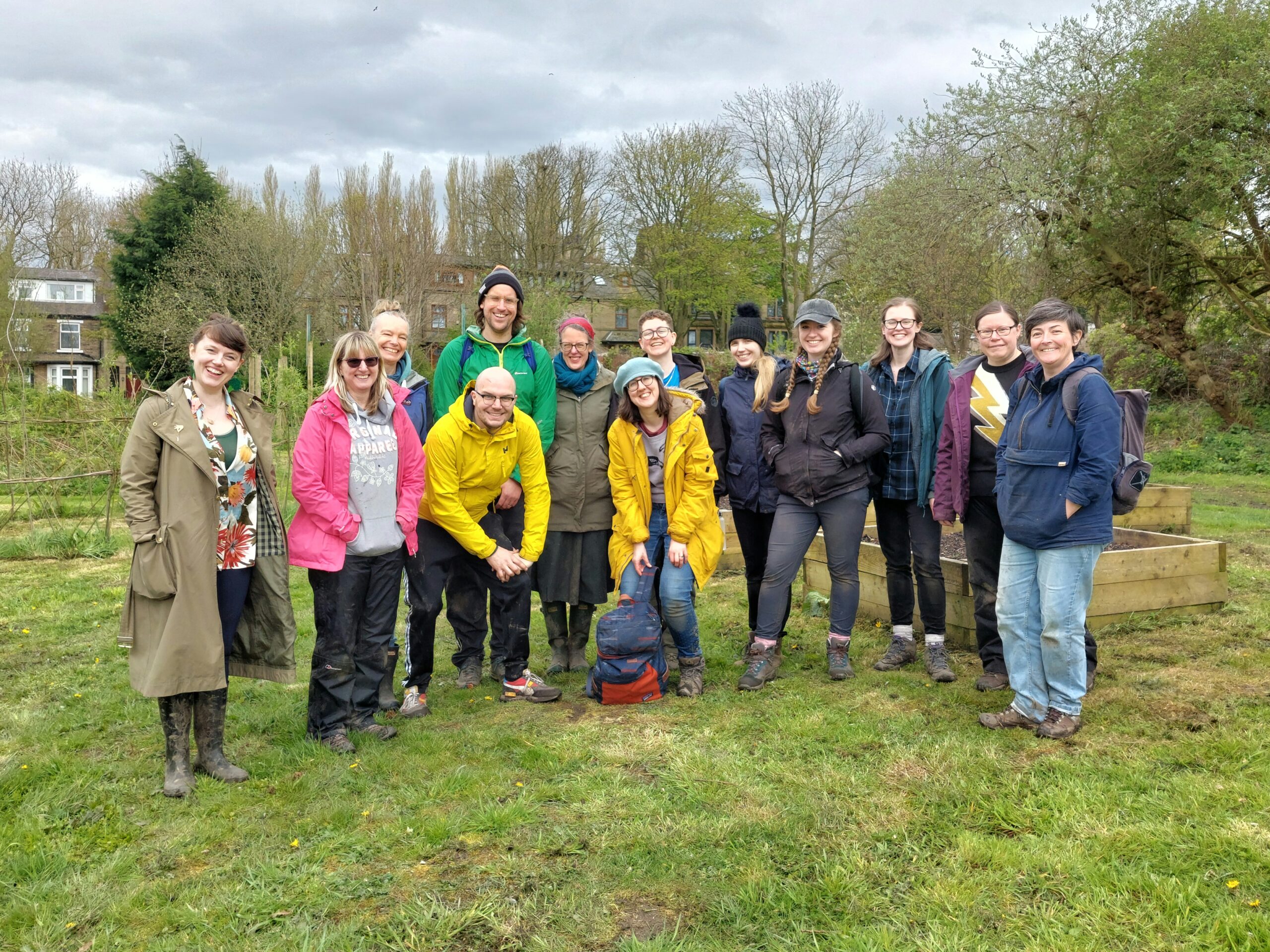 A smiling group of people in outdoor clothes at an allotment