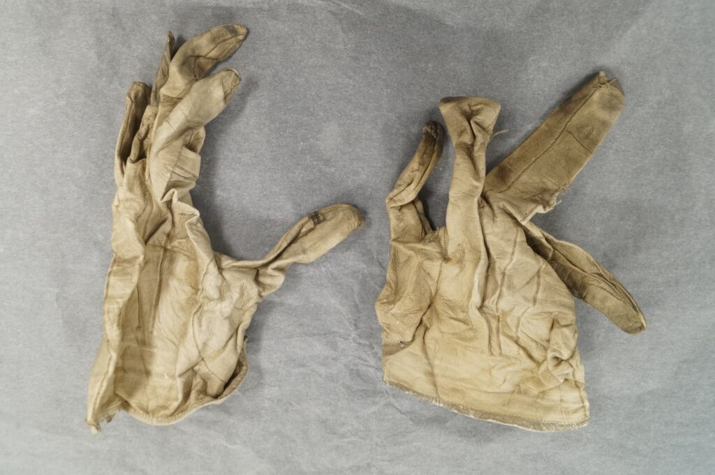 A crumpled and dry pair of cream leather gloves.