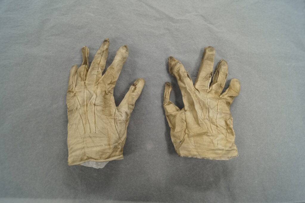 A pair of cream leather gloves on a grey sheet