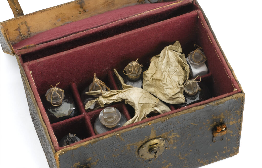 Close-up view inside the leather box, showing glass bottles and a pair of crumpled leather gloves