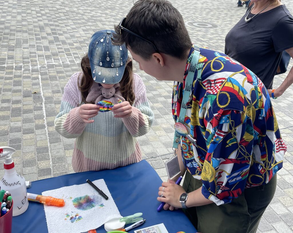 Learning team member in a colourful shirt helps a child with a science activity.