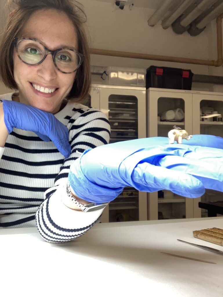 Vanessa wears blue nitrile gloves and holds a small figurine in her palm.